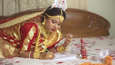 Indische-Bengalische-Braut,-Die-Zigarette-Raucht-Und-Zu-Hause-In-Notizbuch-Mit-Stift-Und-Papier-Schreibt,-Goldschmuck