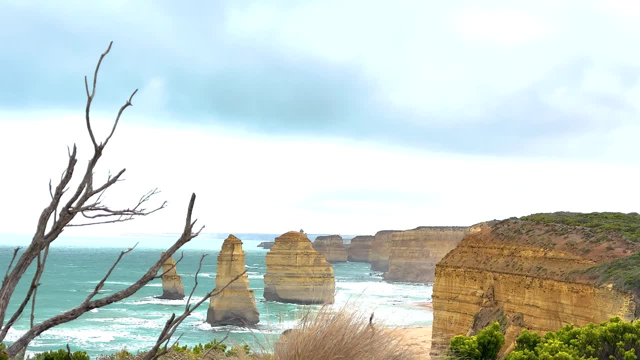 Stunning coastal view of the Twelve Apostles with dramatic cliffs and ocean waves under a cloudy sky