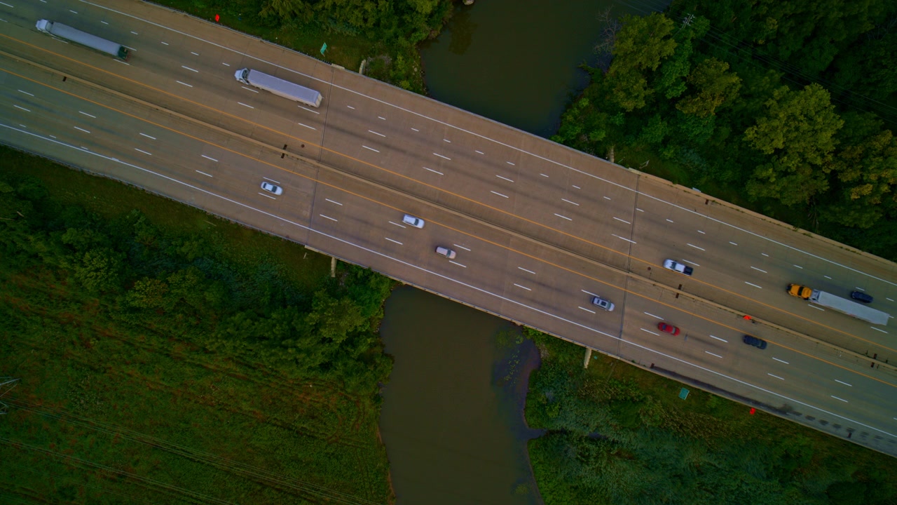 Rekaman drone dari atas yang mengabadikan kendaraan melintasi jembatan di atas sungai di Michigan tenggara.