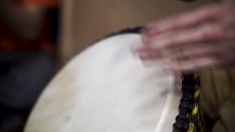 close-up of hands playing a djembe drum