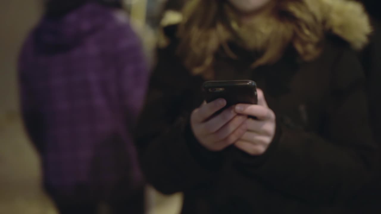 A young woman texts through a crowd
