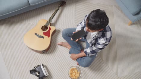 young man relaxing at home with phone and vr headset