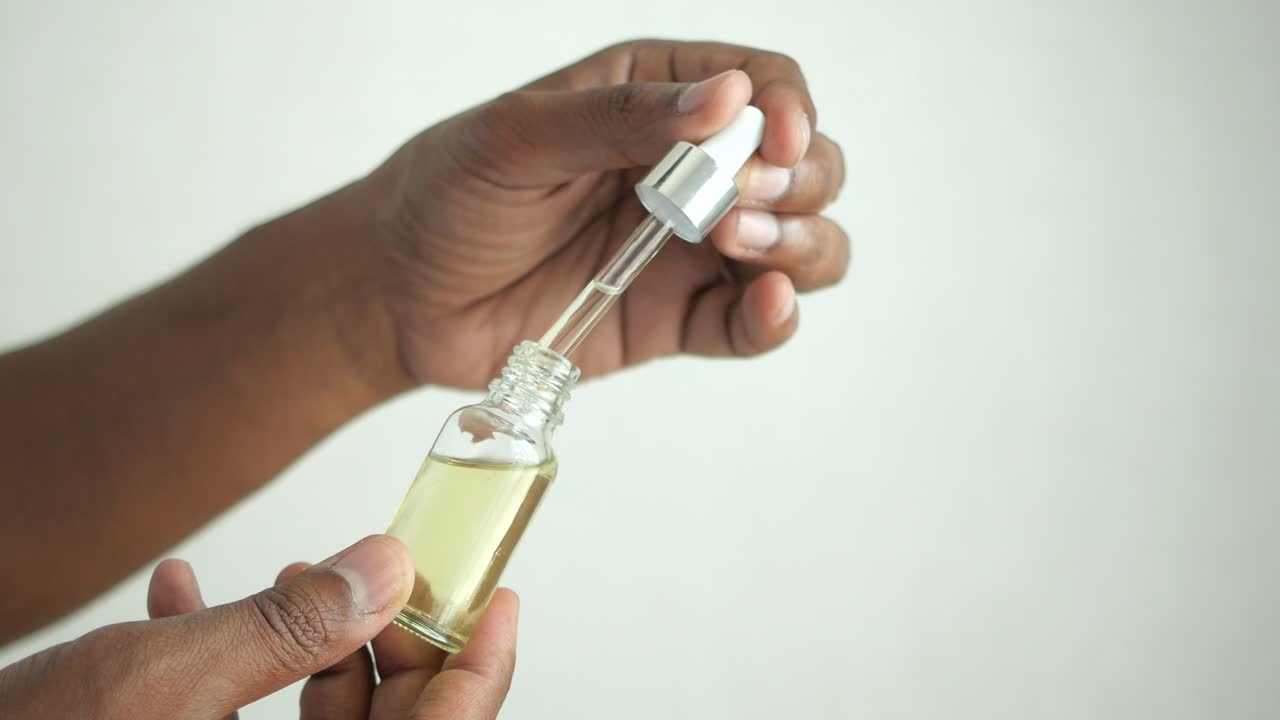 persona que aplica el aceite esencial de la botella gotera