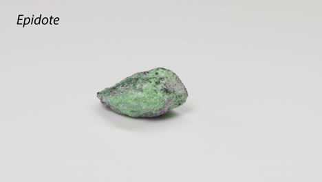 cristal de epidote que gira sobre un fondo blanco