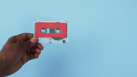 video of african american man's hand holding retro tape with copy space on blue background