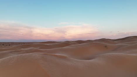 the drone is flying low over the dunes of the sahara desert with the wind blowing sand over the dunes with the sun rising in tunisia aerial footage 4k