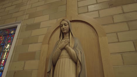 swift push-in to statue of virgin mary in a church chapel with stained glass windows