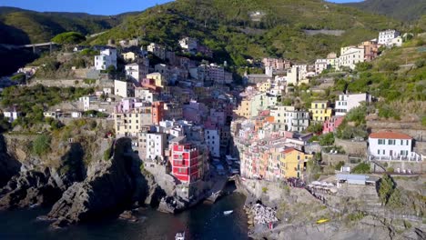 Riomaggiore-town-in-the-Cinque-Terre-Italian-coastline-with-homes-and-buildings-on-cliffside,-Aerial-pedestal-lowering-shot