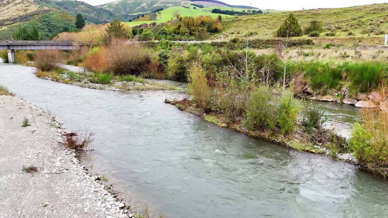 A tranquil river meanders through lush greenery under soft daylight, capturing the serene beauty of Lake Tekapo's natural environment