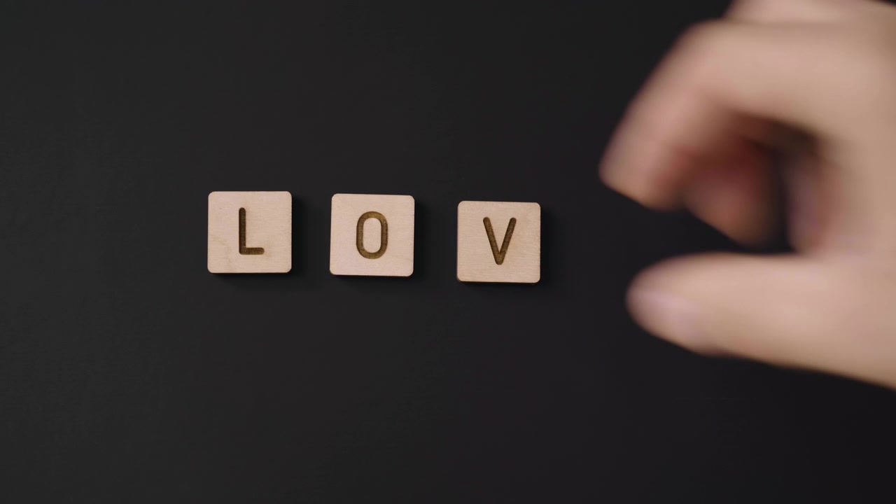 Mano che Compone Lettere di Legno per Formare la Parola Amore