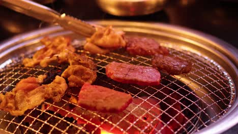 tongs flipping meat on a barbecue grill