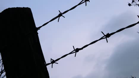 Timelapse-of-gray-clouds-passing-by-against-barbed-wire-fence