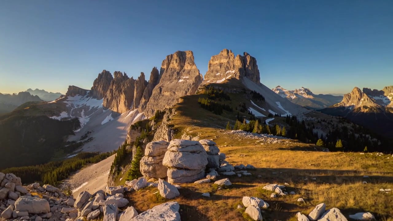Sole calante che sposta la luce, illuminando il massiccio calcareo centrale su un altopiano alpino, rivelando massi