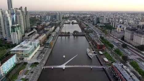 aerial cinematic 4k footage of a drone flying backwards revealing puerto de la mujer or woman's bridge in puerto madero, argentina