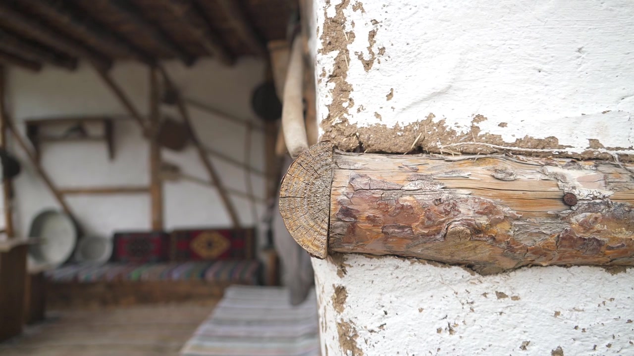 Nærbillede af traditionel bjælke- og pudsvæg i et rustikt hus