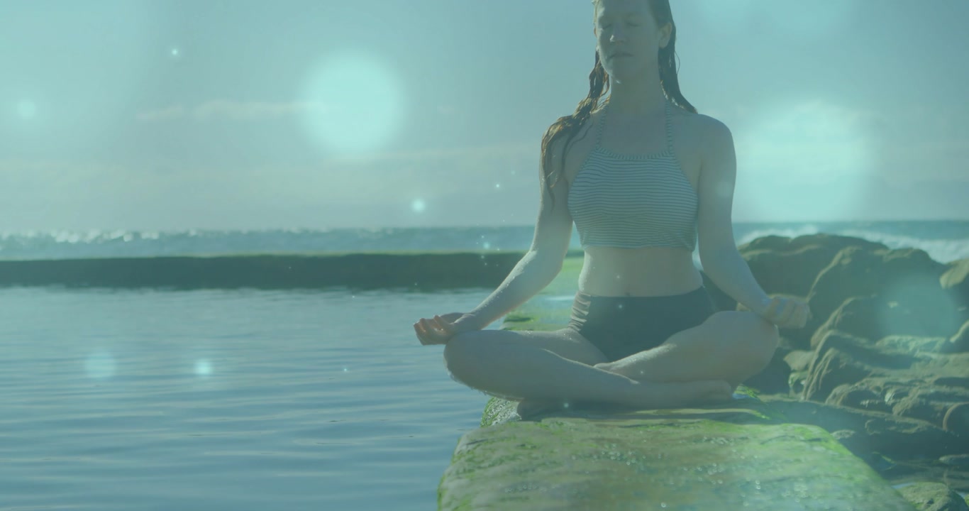 Low-angle camera starting upward, revealing seated woman meditating on jetty and showing calm