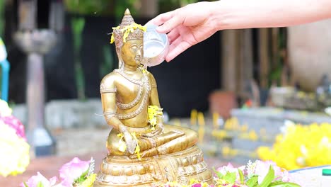 pouring water over a buddha statue in a ritual