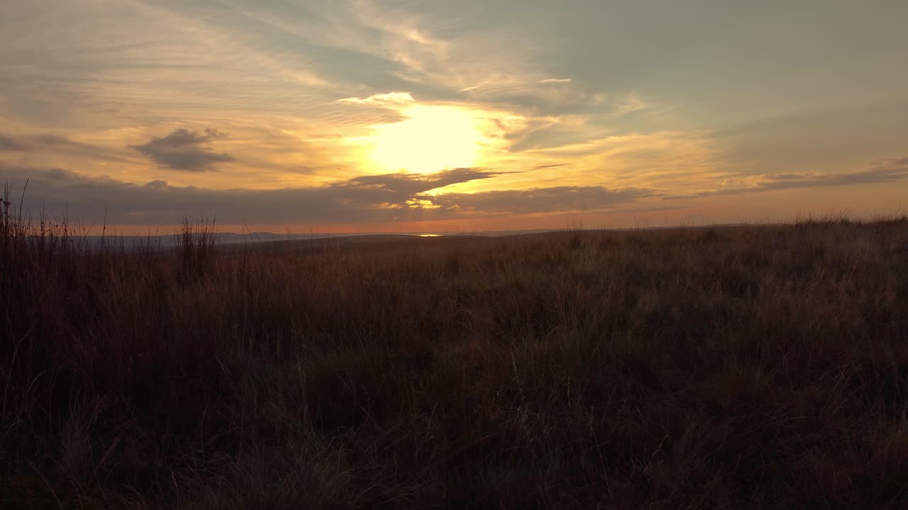 Static Shot of Sunset on Moorland Peak with Dynamic Cloudscape with Different Variations of Yellow and Orange with Muted Grass Colors in Wales UK 4K