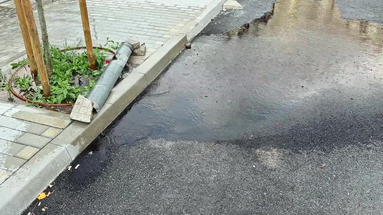 Vettä kerääntyy kadulle sateen jälkeen muodostaen lätäköitä viemärin lähelle kaupunkialueella päiväsaikaan.