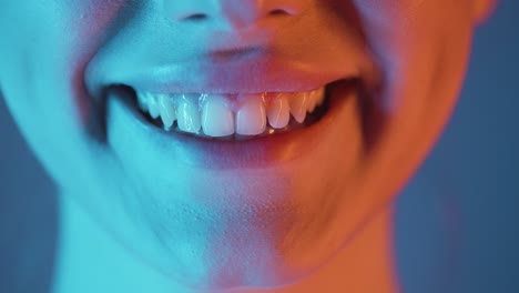 close up of a pretty woman with focus on her lips while she starts to smile and is happy with blue orange contrast in her face