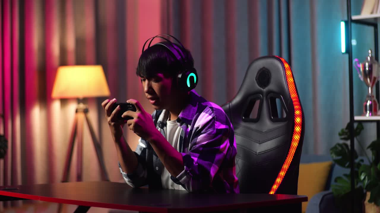 Serious Asian Teen Boy Gamer Playing Video Game On Smartphone