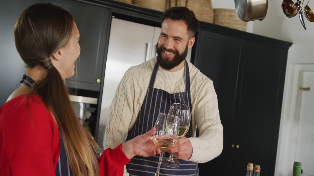video de una feliz pareja caucásica cocinando y bebiendo vino