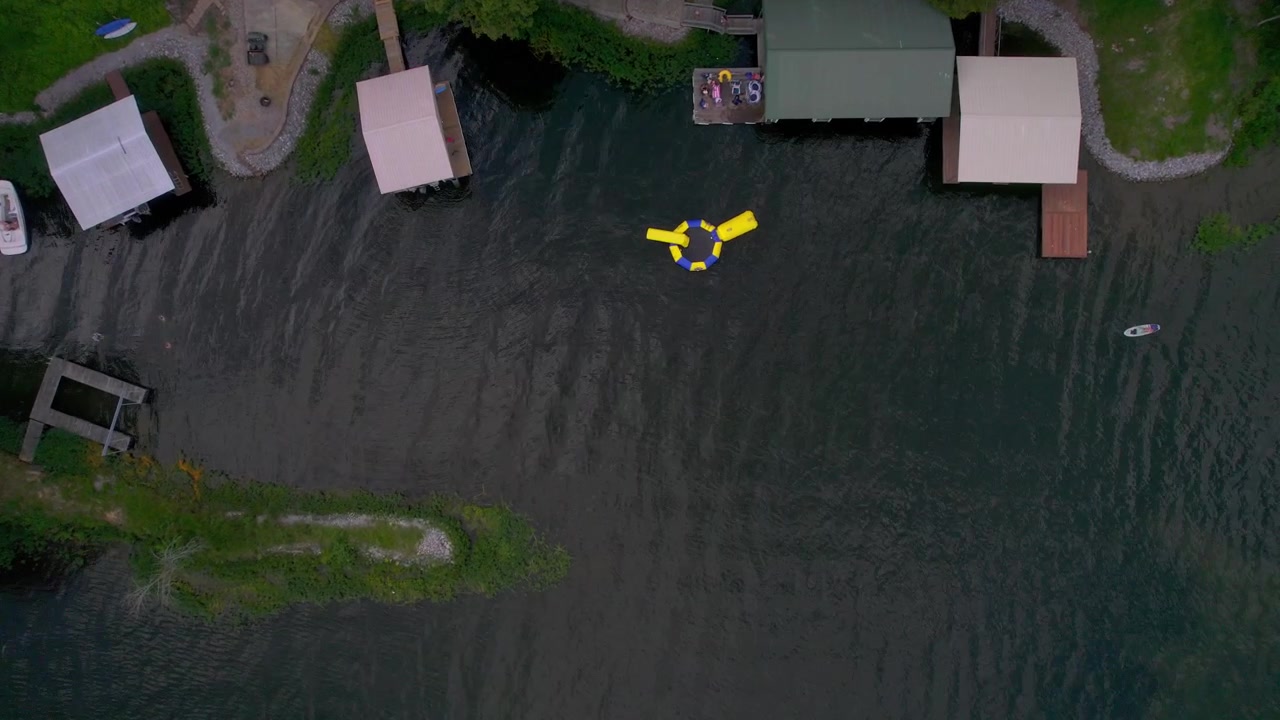Aerial drone view looking straight down at a boat dock, water trampoline, and a boat
