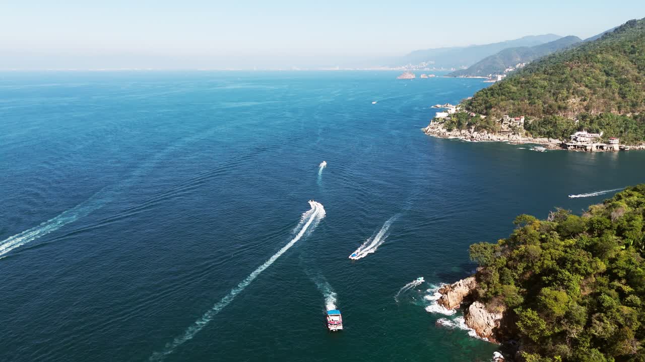 Prospettiva aerea di barche turistiche che navigano le acque blu vicino a una costa montuosa