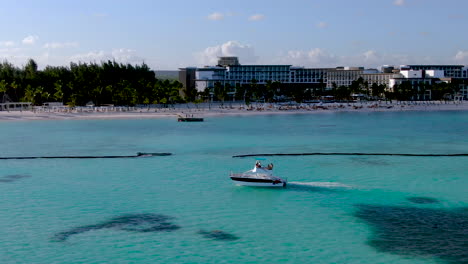 Aerial-of-pleasure-craft-cruising-past-the-white-sandy-beach-at-a-luxury-resort,-Dominican-Republic