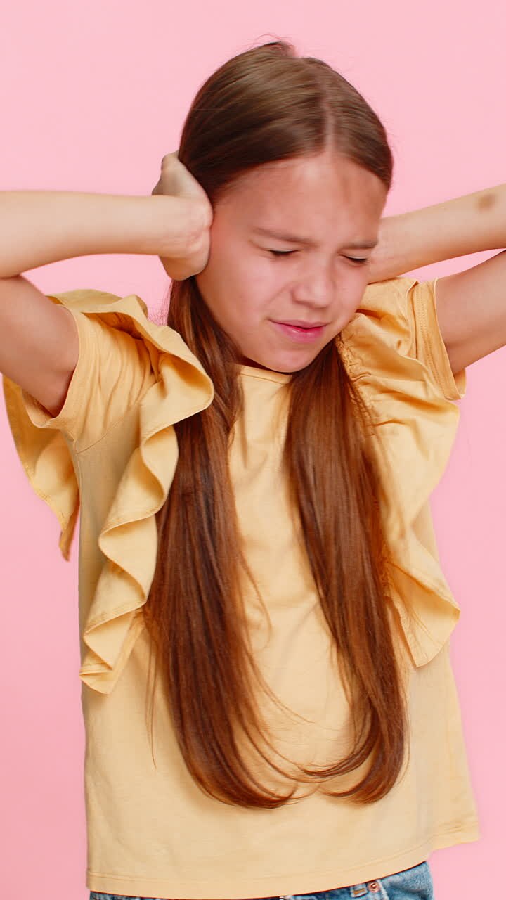 Child girl kid covers ears with hands opens eyes wide showing fear or panic from loud noise or sound