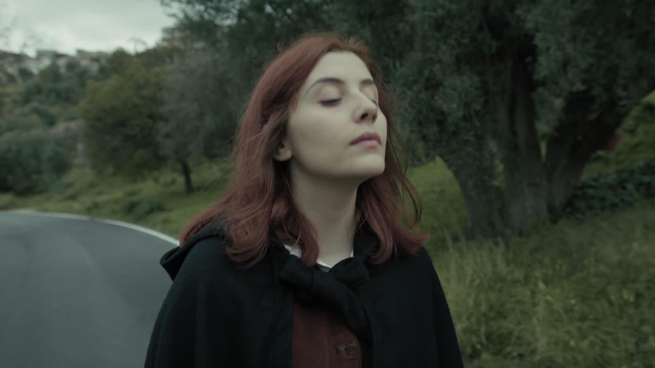 Joven mujer pasea tranquilamente y respira aire puro en un camino de montaña.