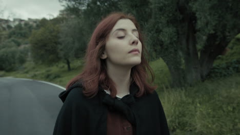 young woman relaxedly walks and breathes pure air on a mountain road