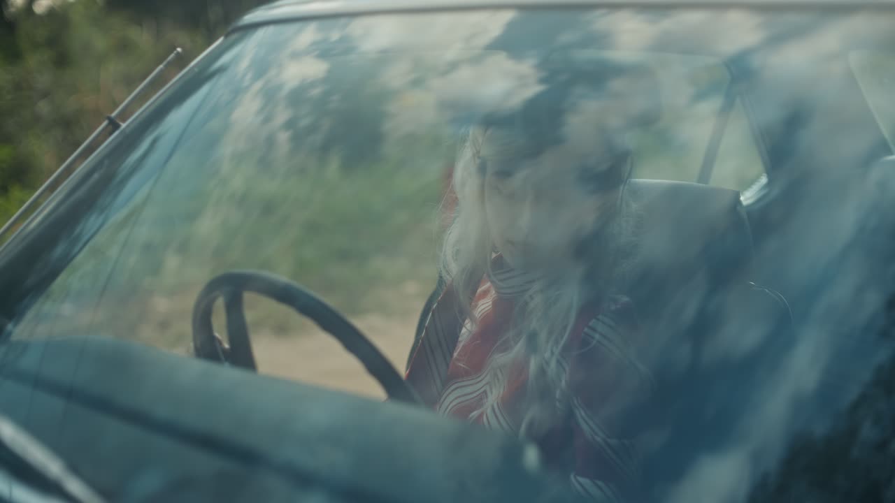 Giovane donna seduta in un'auto d'epoca apre lo sportello