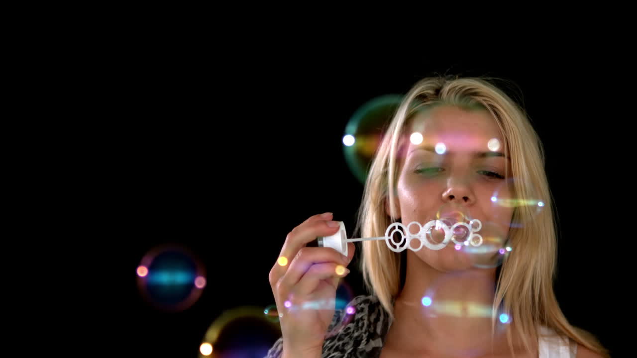 예쁜 금발이 많은 거품을 불고 있습니다.