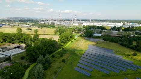 eco friendly solar panel farm on grass field and eco unfriendly industrial factory in background