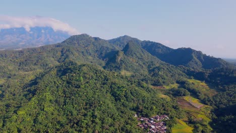 aerial cinematic clip: drone flying over indonesian countryside landscape, village, plantation, forest and hills