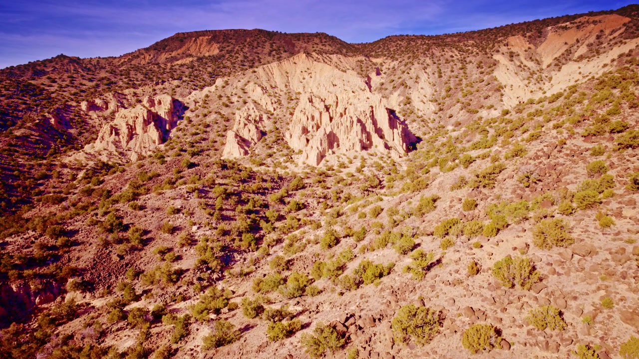 Panorâmica cinematográfica de drone através de falésias do deserto com texturas de rocha vermelha.