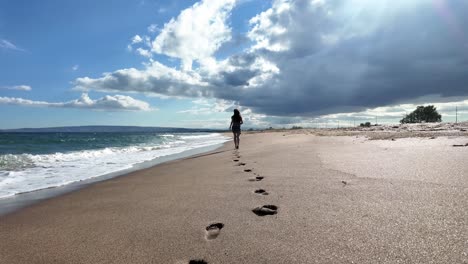 a woman runs along a sandy beach with the ocean in the background