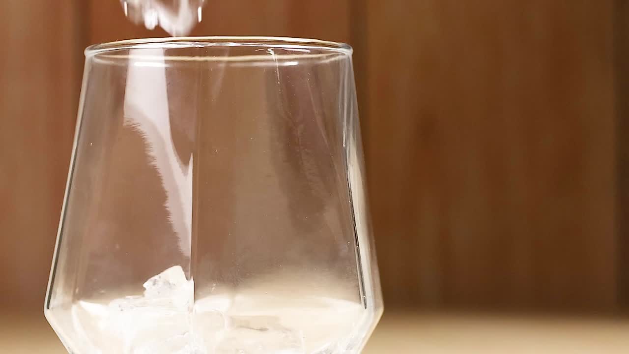cubos de hielo cayendo en un vaso vacío