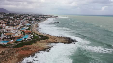 experience the beauty of the sea, big waves, and city from a new perspective with drone footage of a drone flying above the water, capturing the pier in the city and the dark skies