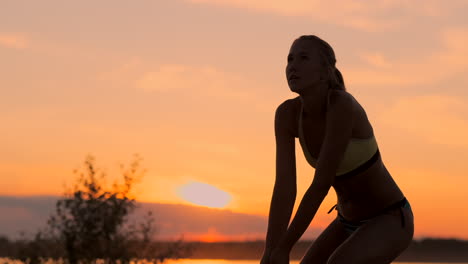 chica atlética jugando voleibol de playa salta en el aire y golpea la pelota sobre la red en una hermosa noche de verano. mujer caucásica anota un punto.