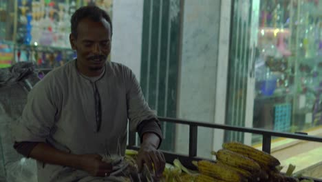 happy man is selling corn on the evening street