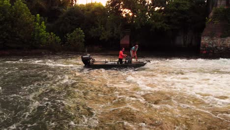 Dos-Pescadores-En-Una-Lancha-Echando-Anclas-En-Los-Rápidos-Junto-A-La-Presa-Del-Río