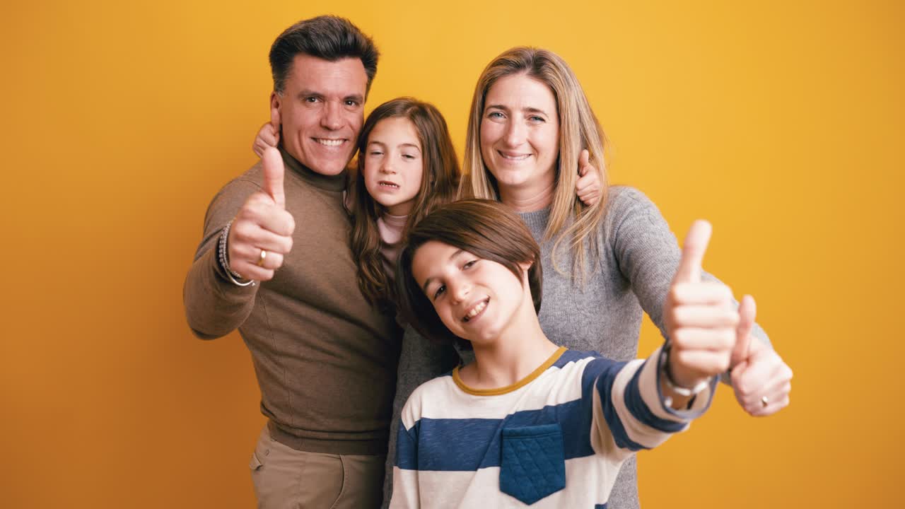 Happy Family Smiling and Giving Thumbs Up on Yellow Background
