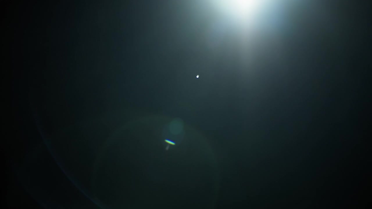 Blue lens flare fading out to black background in slow motion