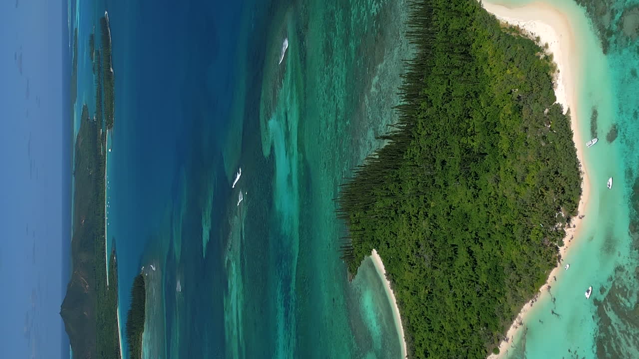 Luftbillede, der trækker sig tilbage fra Ilot Moro, afslører det klare vand ved Isle of Pines i baggrunden.