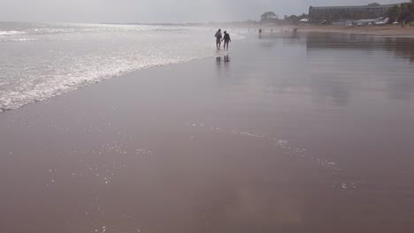 Silueta-De-Dos-Personas-Caminando-Por-La-Playa-En-Bali,-Seminyak,-Indonesia