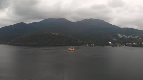 right panning aerial over lake ashi in hakone with orange pirate ship transporting travelers