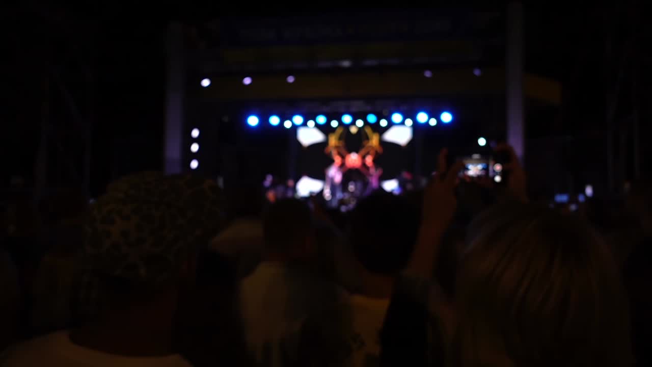 Concerto sul palco. Folla di persone e musicisti sulla scena. Fuori fuoco