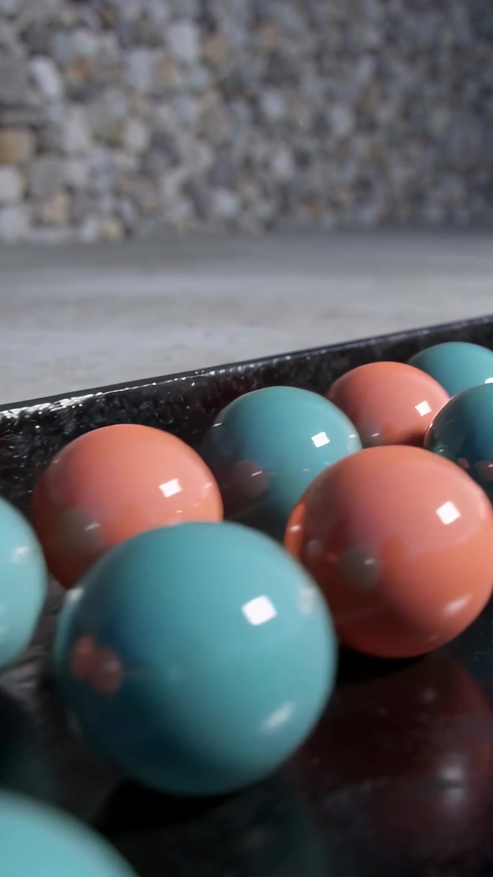 Vertical video: Rolling teal coral spheres shifting on dark tray after frame shift, with mosaic
